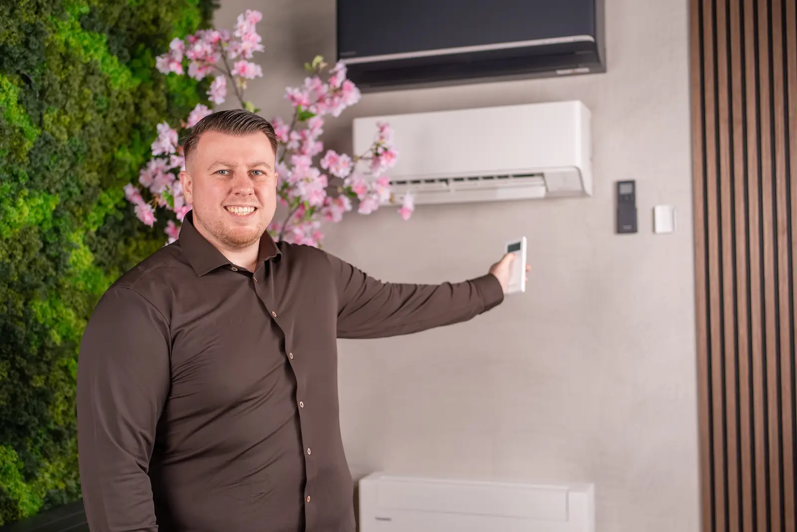 Giovanni Kokken toont een wandmodel airco in de Jadikoel showroom met plantenwand