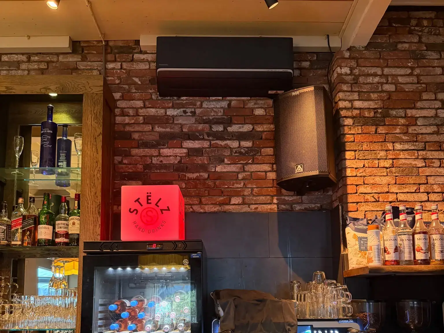 Zwarte Panasonic airco wandunit boven de bar in een restaurant in Delft, geïnstalleerd door Jadikoel