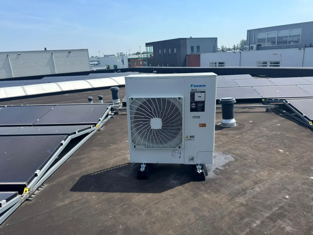 Daikin SkyAir buitenunit tussen de zonnepanelen op het platte dak van een tankstation in Gouda
